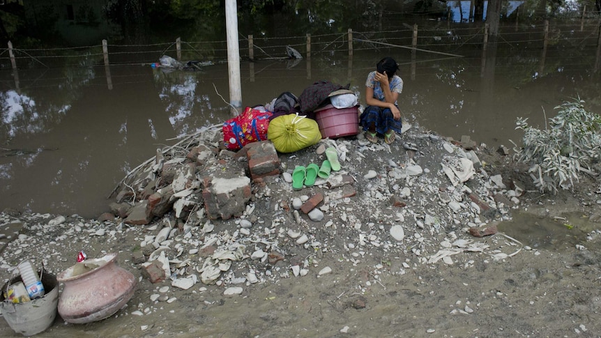 A resident sits on high ground near a flooded area in Kalay