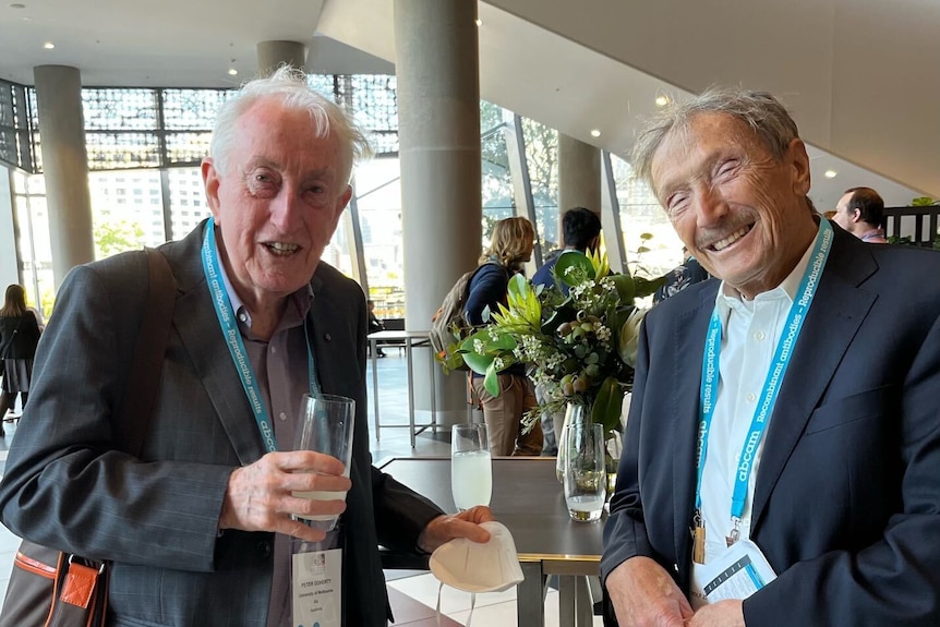 Peter Doherty and Rolf Zinkernagel leaning on a table. Peter is holding a drink