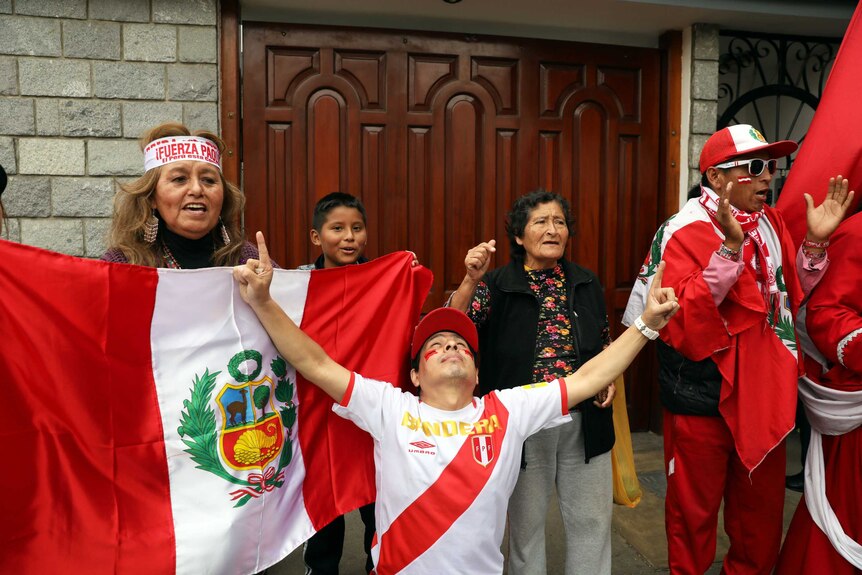 Fans waving flags celebrate outside the house of Peruvian player Paolo Guerrero's mother's house