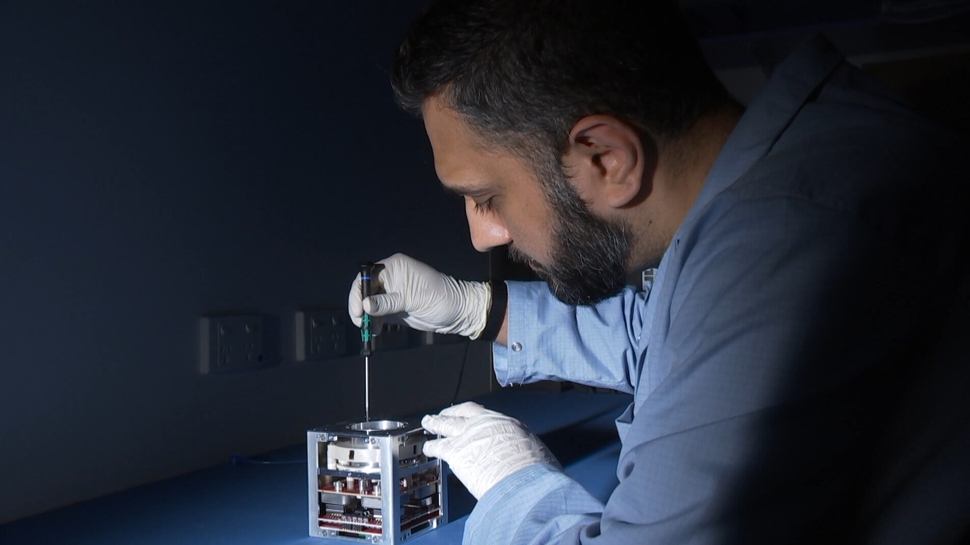 Un hombre usa un destornillador en un pequeño cubo de alta tecnología.