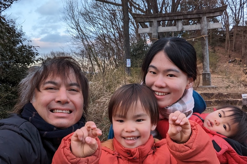 A young family smile at a landmark in Tokyo.