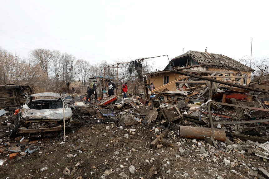 Authorities at the site of a residential home and car destroyed by a Russian air strike.