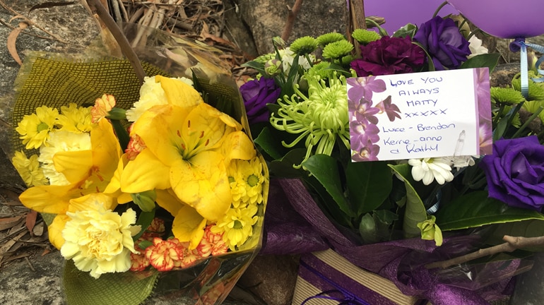 Picture of flowers laid by roadside near the crime scene where investigators are looking for Matthew Leveson's body