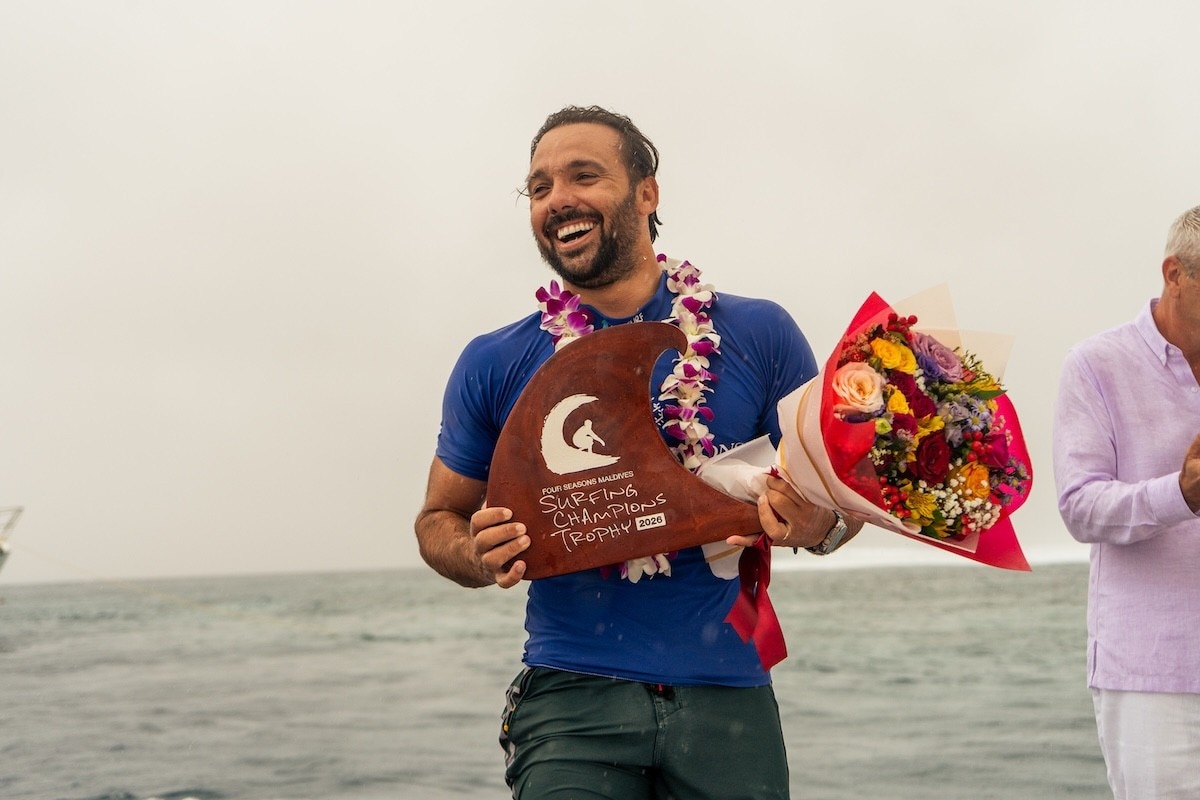 surfing champion Caio Ibelli standing holding championship trophy and flowers