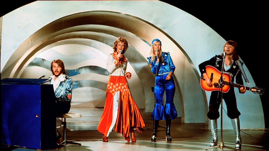 Abba perform on stage, an arch structure is in the background