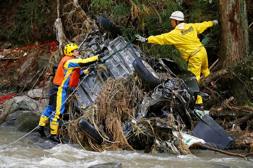 Rescuers pulling out a car from a river bank.
