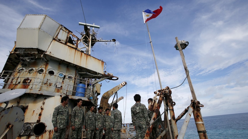 Filipino marines standing on the deck of a rusty ship. 