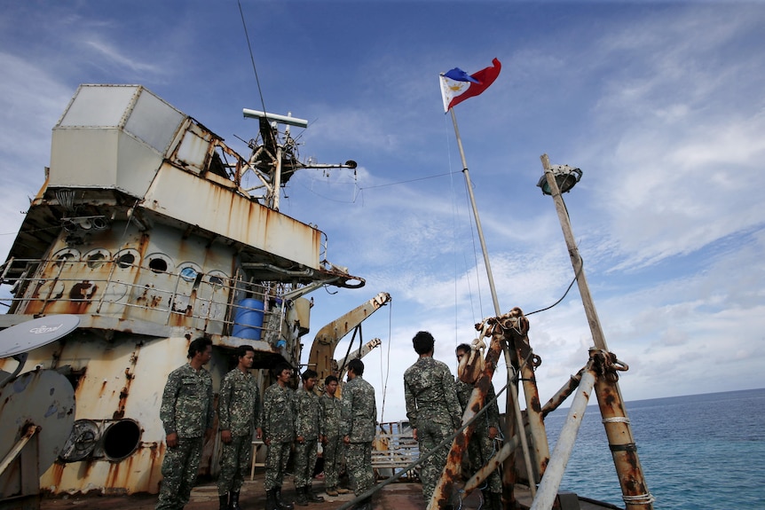 Filipino marines standing on the deck of a rusty ship. 