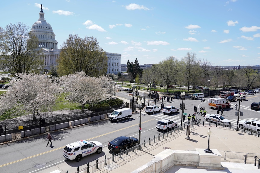 Police officers surround the scene after a car crashed into a barrier. The Capitol Hill building can be seen in the background.