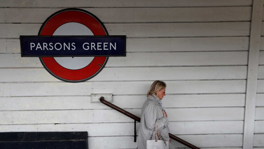A woman walks down a set of stairs near a sign saying "Parsons Green"