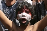 An anti-government protester boy with his face painted in the colours of Yemen's national flag shouts a slogan