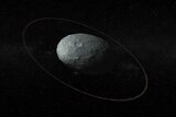 The dwarf planet Haumea, which looks like a potato-shaped rock, in space and surrounded by a thin ring of debris