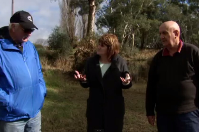Three people gather to talk about flooding in their town