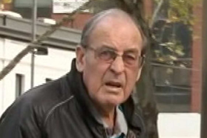 John Laidlaw squints at the news camera as he walks into a court building.