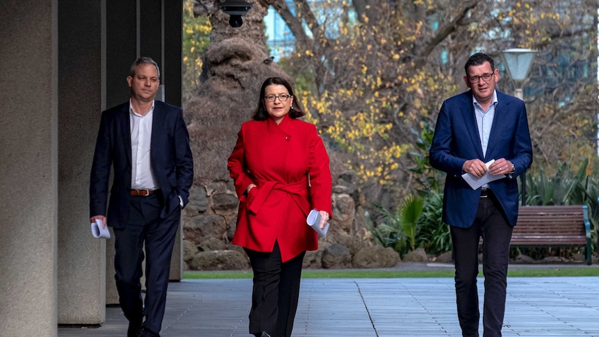 Brett Sutton,  Jenny Mikakos and Daniel Andrews walk along a footpath.