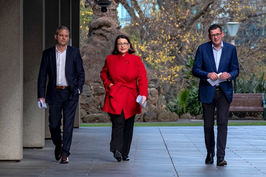 Brett Sutton,  Jenny Mikakos and Daniel Andrews walk along a footpath.