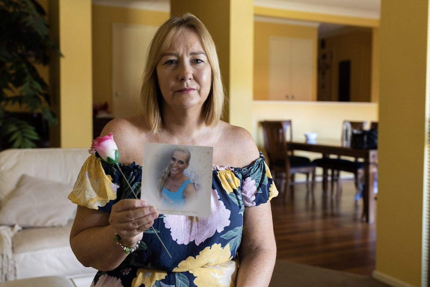 Janine Mackney, aunt of Breanna Robinson, holding a rose and photo of Breanna Robinson.