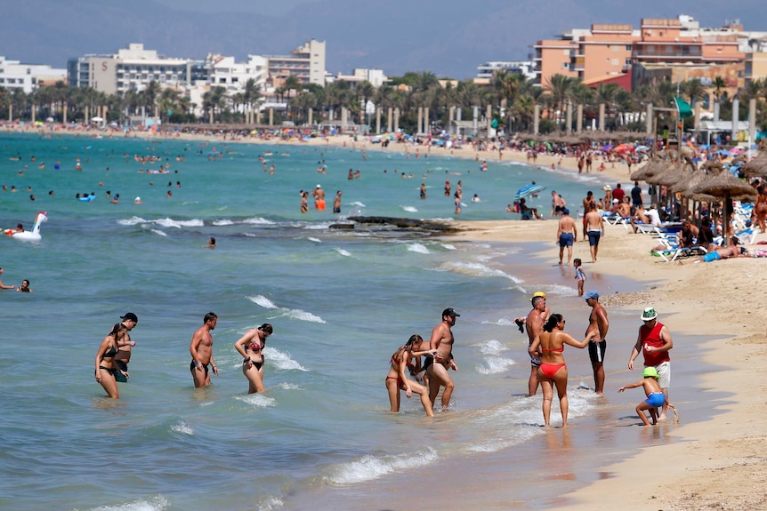 Shirtless people enjoy the beach in Majorca, Spain