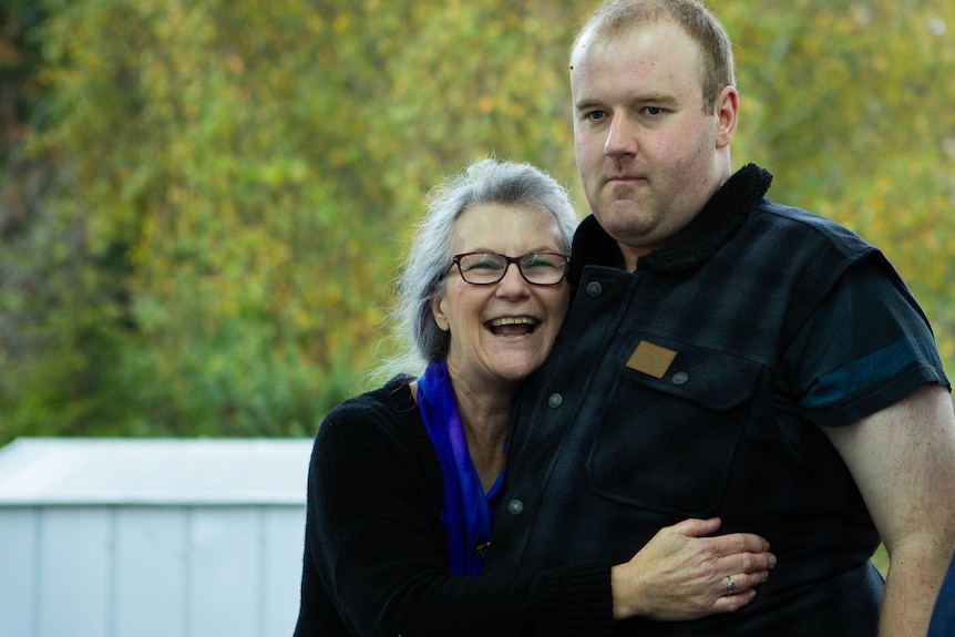 A mother and son hug and smile together for the camera.