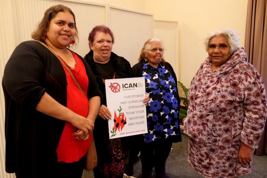 A group of four women standing and smiling.