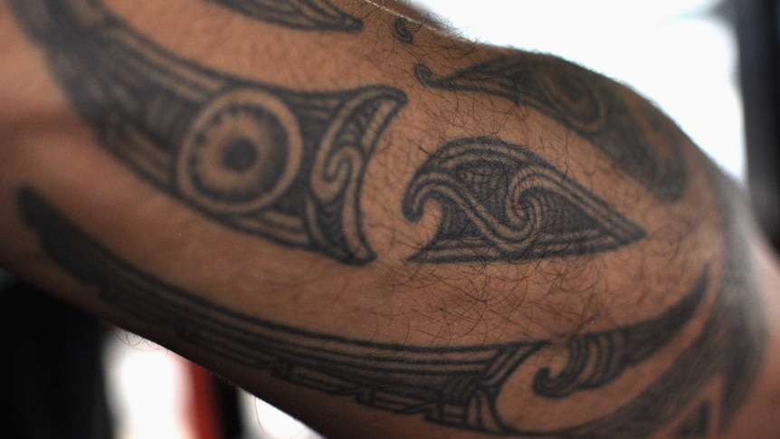 A close-up of a traditional Maori tattoo on the arm of a man.