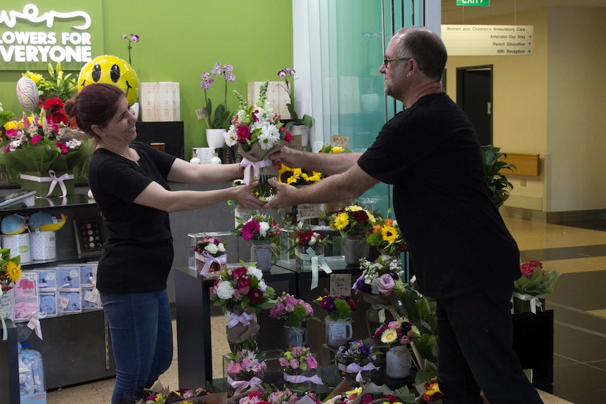 Jock Brown hands flowers to a customer
