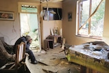 A man cries as he sits in his house damaged by shelling. Kitchenware, ceiling fixtures, furniture are seen damaged.