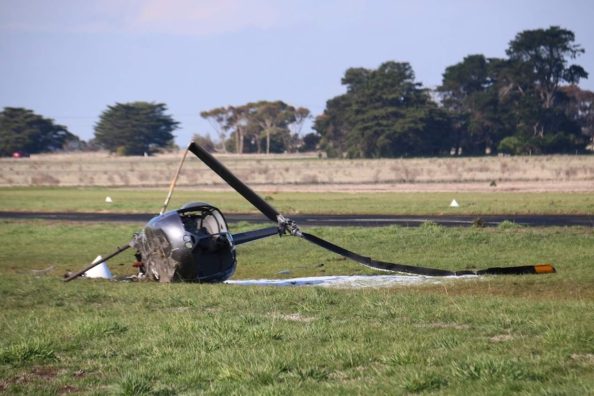 The wreckage of a Robinson R44 helicopter is seen on the ground, lying on its side, after it crashed.