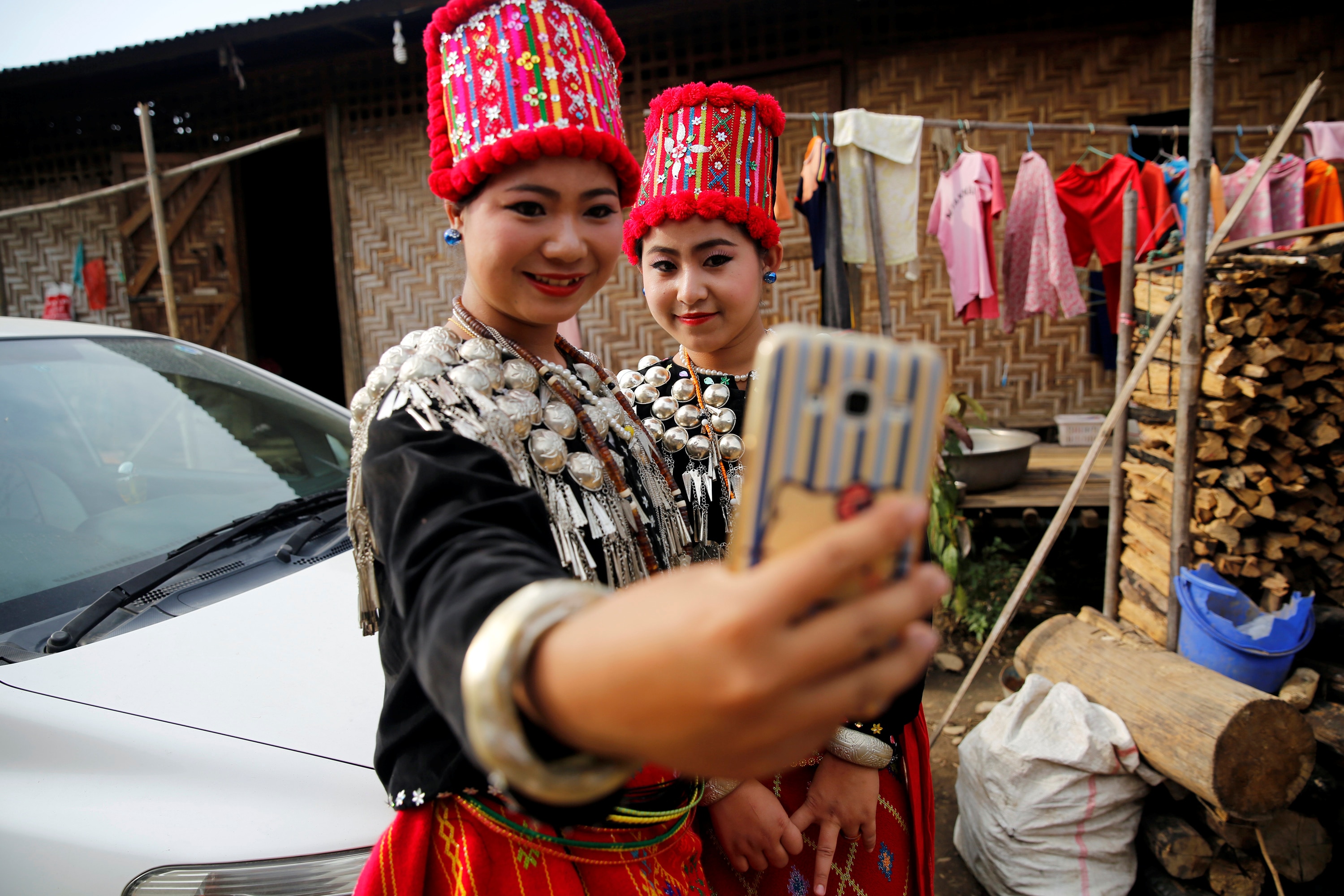 Women wear red traditional beaded ethnic dress and take selfie with phone.
