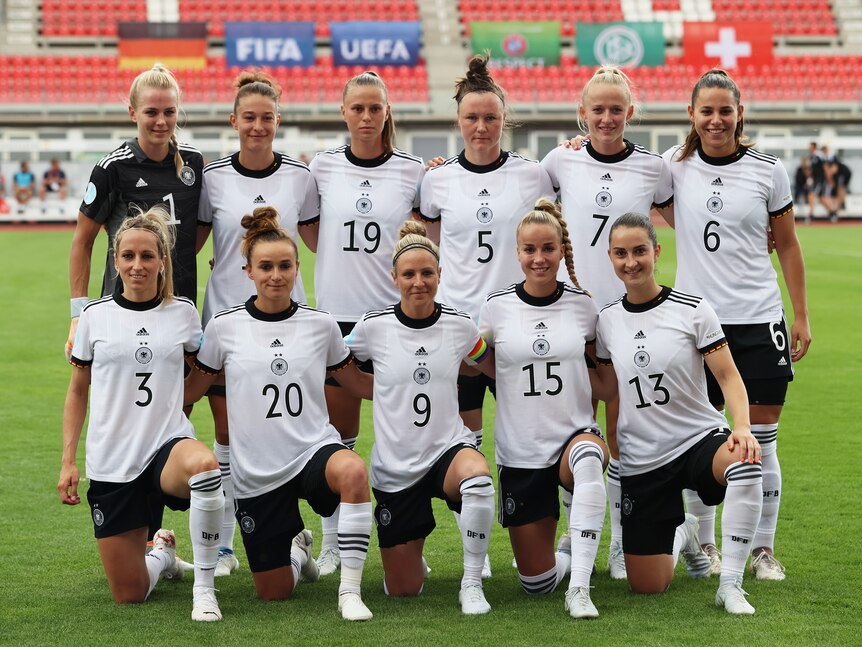A women's soccer team wearing white and black poses for a photo