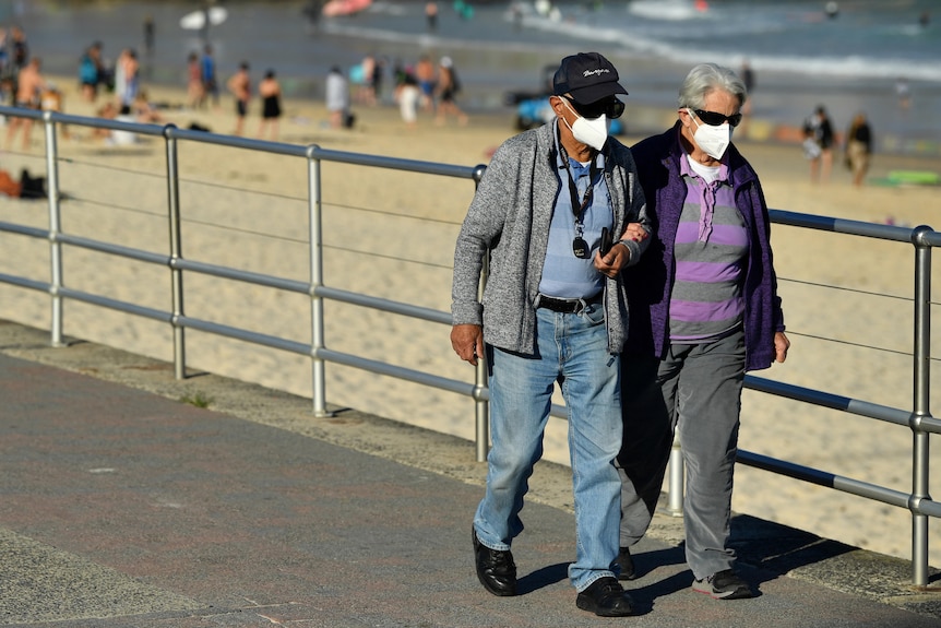 Couple walking along Bondi Beach