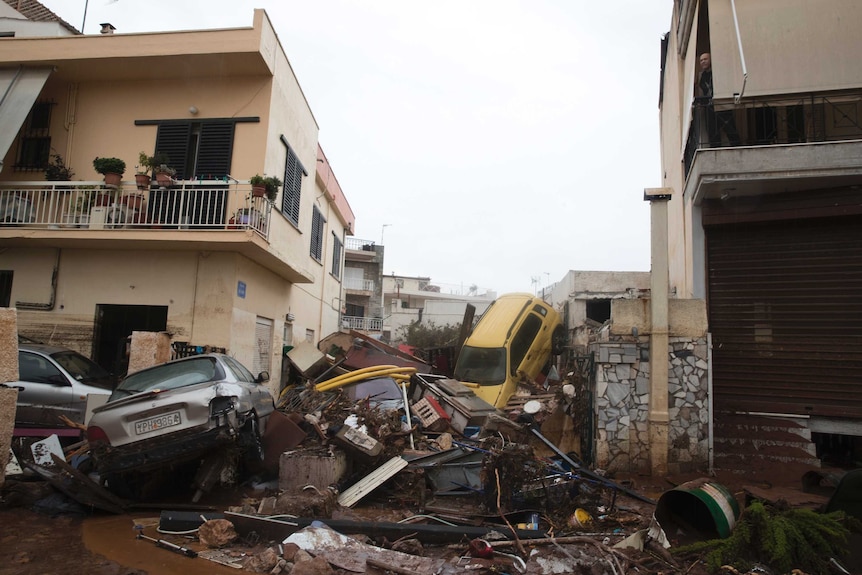 A man looks out from his home over piles of vehicles in the municipality of Madra western Athens.