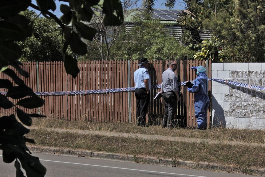 Police and forensic officers stand at a fence with police tape on it at a home at Cranbrook.