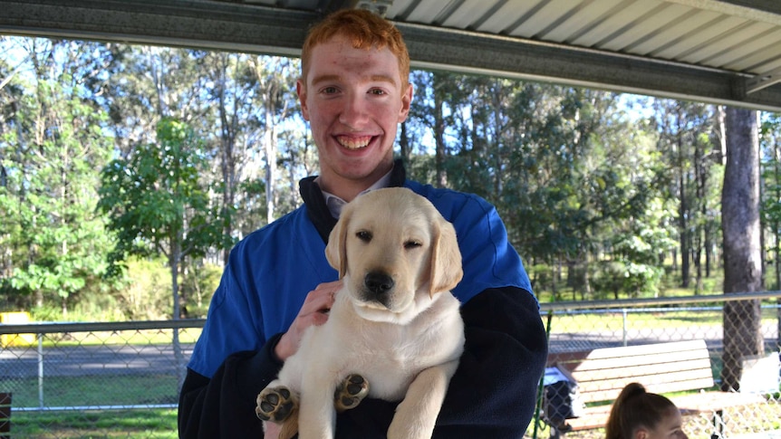 CJ Whitney carries a guide dog puppy