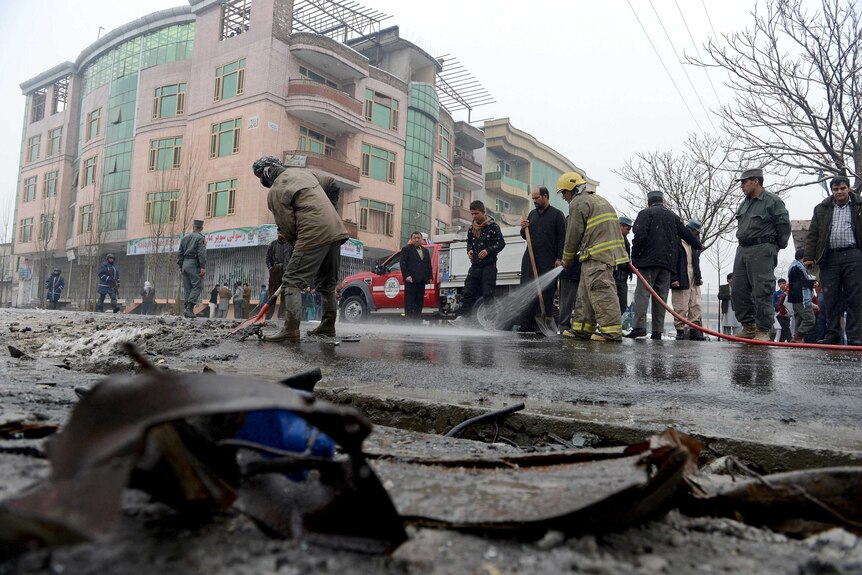 Firefighters wash road after suicide attack in Kabul.