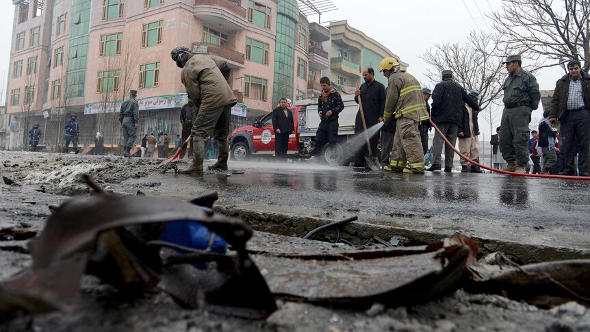 Firefighters wash road after suicide attack in Kabul.