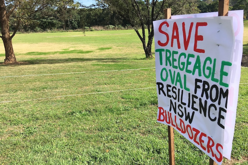 A handmade sign protesting against a proposed temporary housing development on an oval.