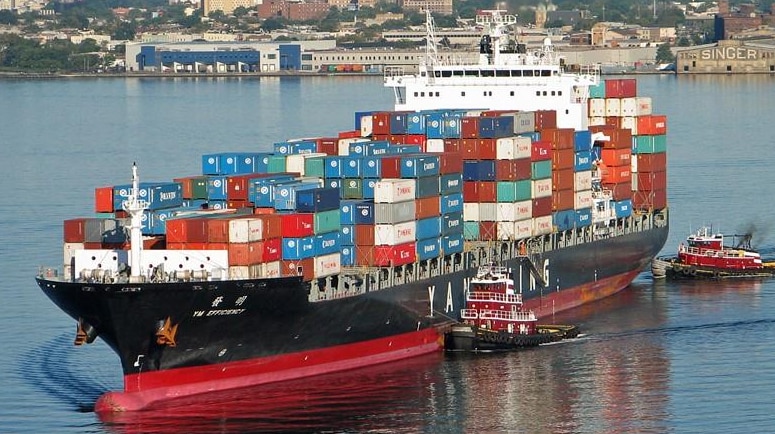 A large container ship close to the coast carrying a large load of shipping containers