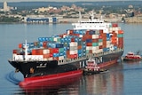 A large container ship close to the coast carrying a large load of shipping containers.