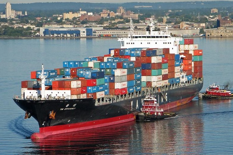 A large container ship close to the coast carrying a large load of shipping containers.