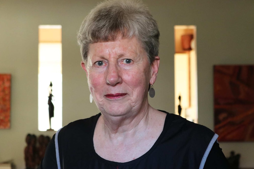 A woman wearing a black shirt and silver earrings looking into the camera.