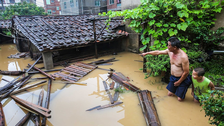 Residents look at an inundated house as they stand in floodwaters in China.