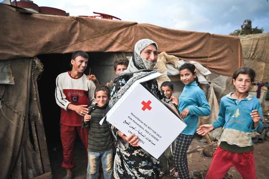 A family smiling after receiving a hygiene kit from the Red Cross.