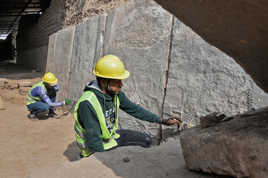 Workers excavate the rock carving with brushes. 