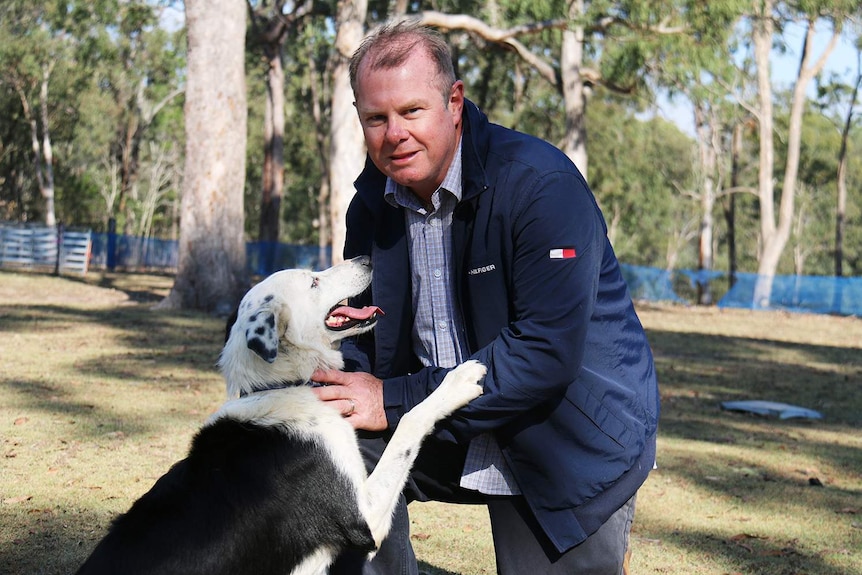 Damien Veneris kneels with his dog Crush