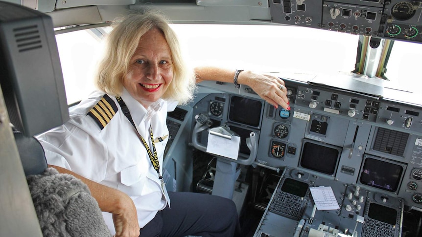 Retired pilot Pam Jensen in uniform while in the cockpit of a passenger plane.