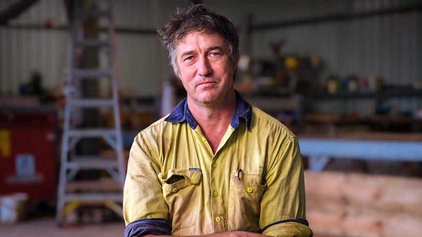 A man wearing a yellow and blue work shirt.