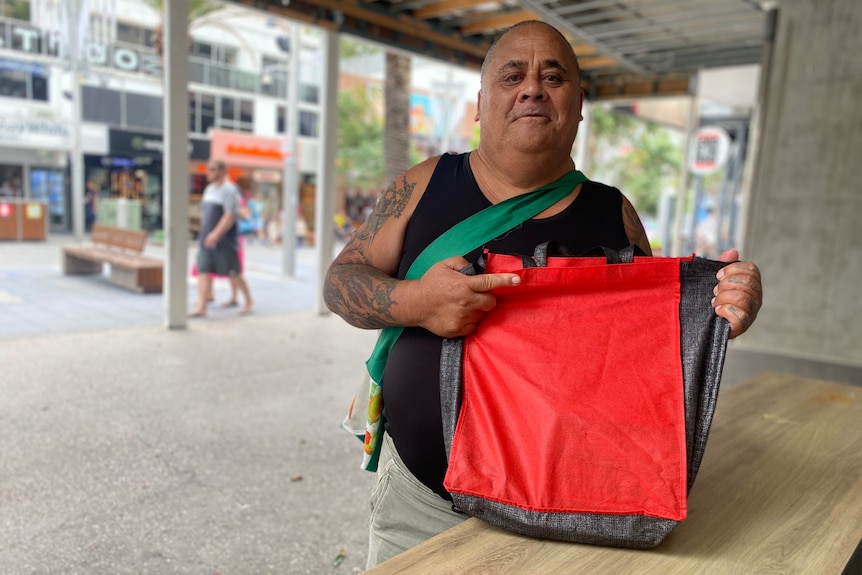 a man holding a reusable shopping bag outside a Gold Coast food bank