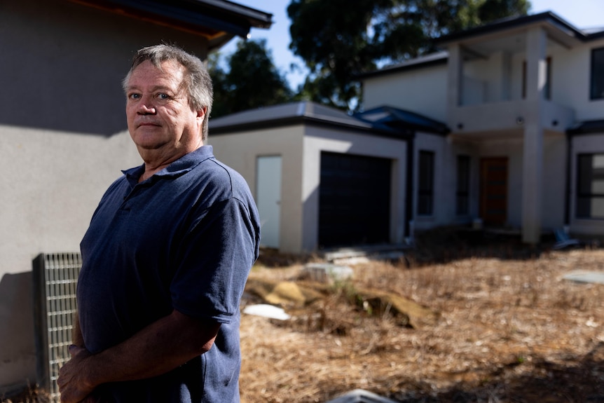 A man standing near his unfinished home