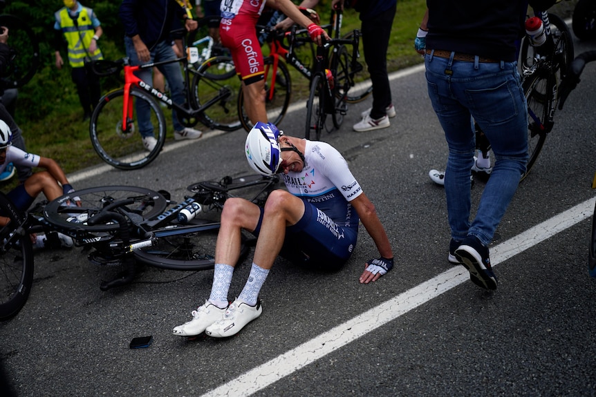 British cyclist Chris Froome grimaces as he sits on the road next to his bike after being in a crash.